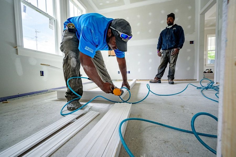 Two-man crew fitting trim in a renovated room